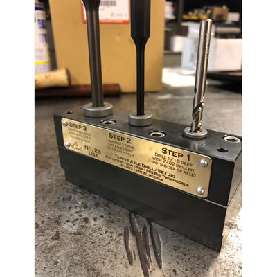 Used to remove & install the tappet rollers. Will drill out old axle ends, drive out old axle, installs new rollers and sets ends of new axle. Currently the best tool available for a professional result. 
- Fast, easy, and precise replacement of tappet rollers.
- Fits lifters with a .730" to.740" body diameter, .850" to .855" roller diameter, and .355" to .370" roller width 
- Will not fit Evo or Twin cam lifters 
- Precision machined with very tight tolerances for a perfect fit 
- Lifter will not move around when performing operations 
- Type III mil spec hard anodized finish for incredible durability 
- Easily clamps into vise to make the whole job easy 
- USA made. 
Instructions how to use. 
Step 1: drill out ends of old axle. 
Use included 7/32" drill bit and drill about 1/16" into each side of the old tappet axle. Lightly oil the drill bit before putting in through the hardened drill bushing.  Be sure to blow chips out in between drilling the two sides of the lifter. 
Step 2: Drive out old axle. 
Carefully drive out the old tappet axle using the included pin punch.  This should take a few firm strikes from a 16oz ballpeen hammer.  If 2-3 firm strikes aren't enough to start moving the old axle out, take out the lifter and move it back to station/step 1 and drill out a little more of the end of the axle before continuing again to step 2 and driving the axle out. 
Step 3: Install new roller assembly and set the ends of new axle. 
Install new/replacement roller assembly and axle into lifter body.  New axle should slide right through lifter body without being forced.  Set lifter assembly into station/step 3 of the tool and use the included roll pin punch to lightly set the ends of the new axle on each side.  This should take just 2-3 light/medium strikes with a 16oz ballpeen hammer. 
Its best to flip the lifter back and fourth a couple of times between the first few light strikes with a hammer.  Axle should remain centered within the lifter body, with an equal amount of the axle protruding out of each side.  